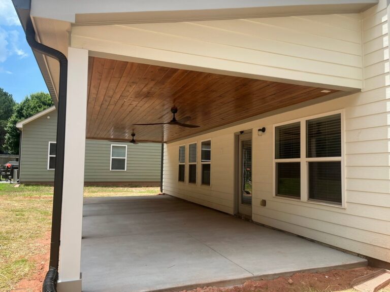 Finished covered porch with a wood-clad ceiling and ceiling fans built by Roof Works