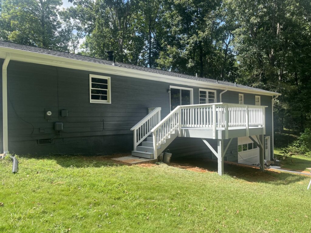 A raised deck with a white rail and steps, built by Roof Works