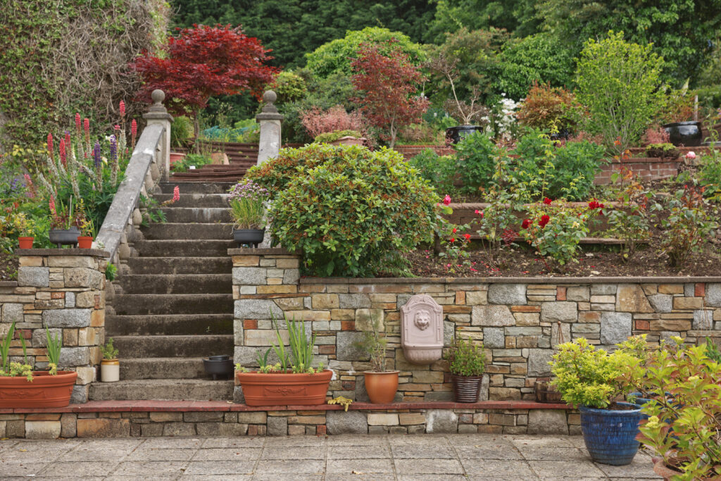 Terraced natural stone retaining walls with steps and planted garden beds