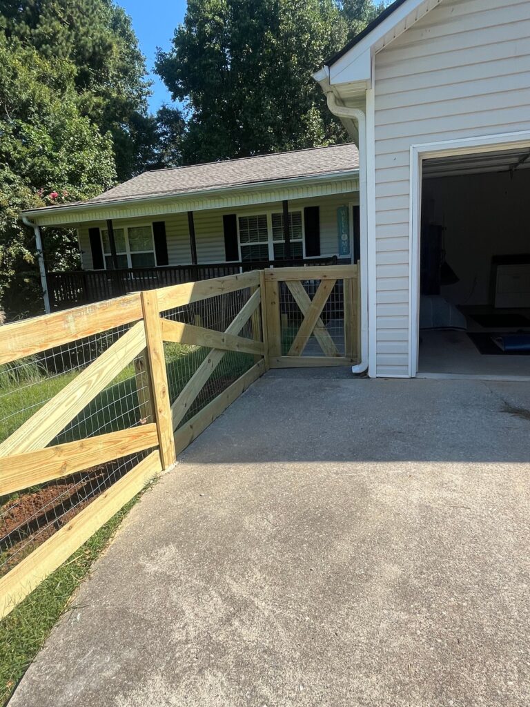 Wood fence gate with a cross buck panel built beside a garage entry
