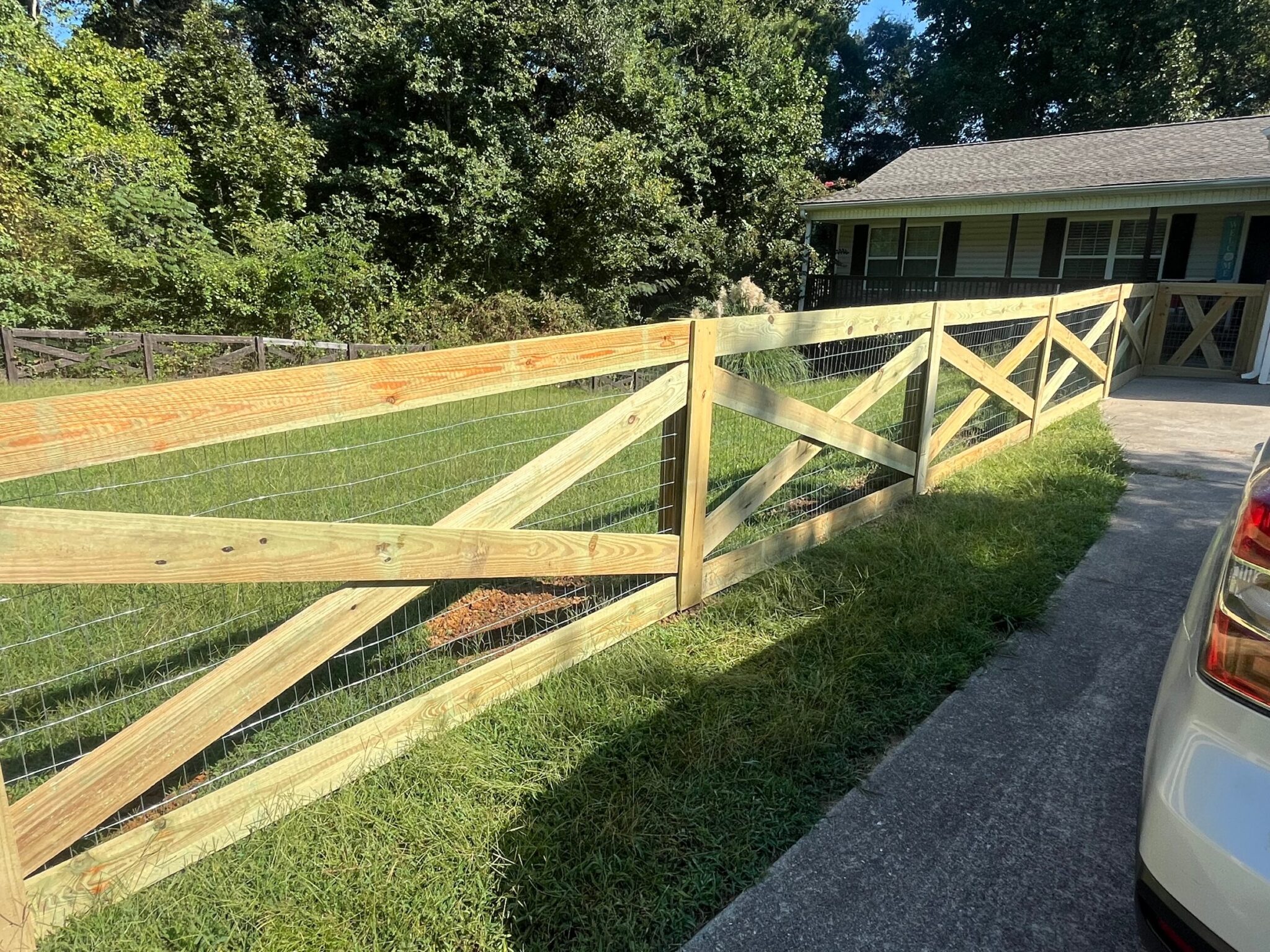 Wood post and rail fence with wire mesh installed along a driveway in Rockmart, GA