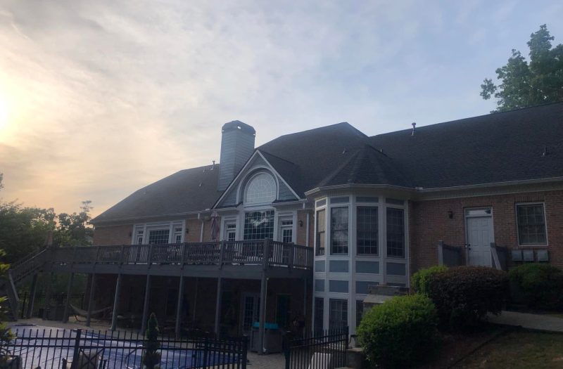 Large multi gable brick home with a finished dark shingle roof