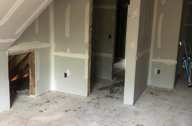 Newly drywalled room with a framed fireplace opening and two doorways