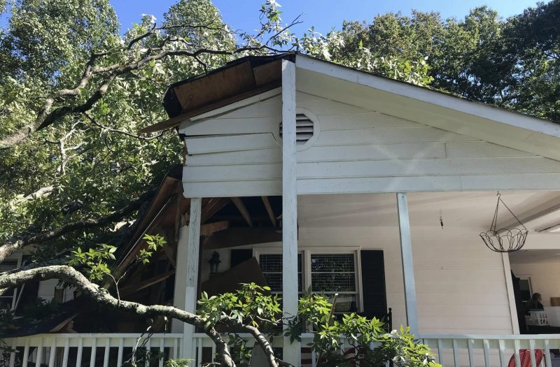 The porch roof of the same house crushed by the fallen tree