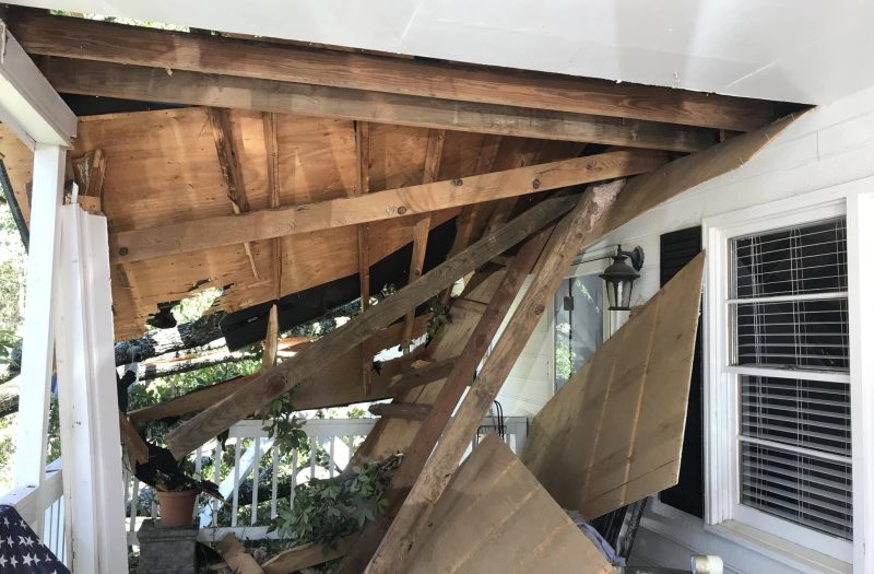 Daylight showing through the torn-open porch rafters, seen from underneath