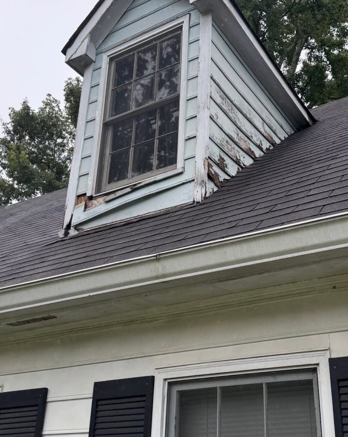 A worn dormer window and siding before Roof Works replaced them