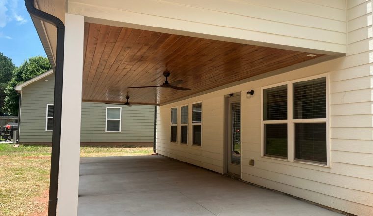 Finished covered porch with a wood-clad ceiling and ceiling fans built by Roof Works