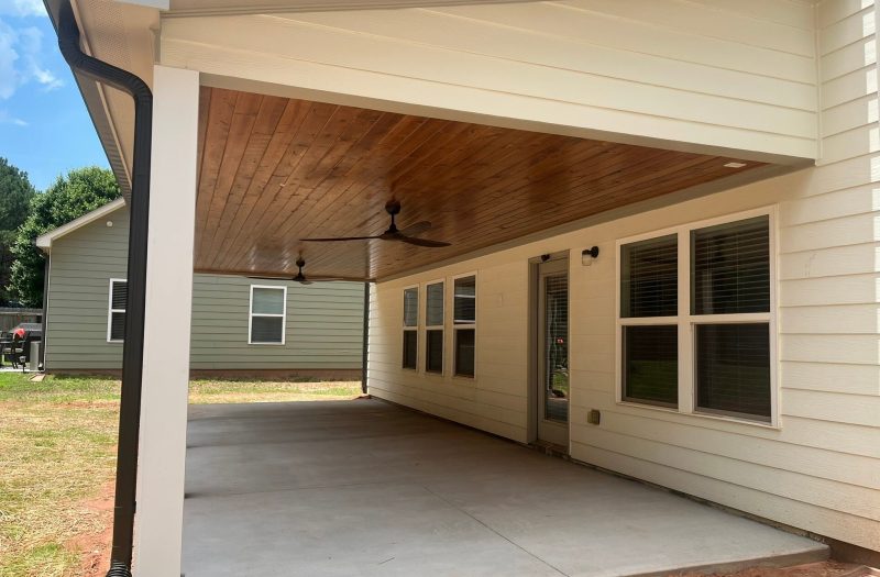 Finished covered porch with a wood-clad ceiling and ceiling fans built by Roof Works