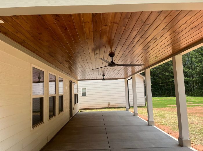 Covered porch with a wood-clad ceiling built by Roof Works